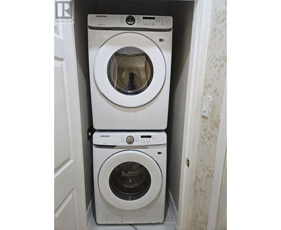 A stack of three white Samsung washing machines in a small laundry room.