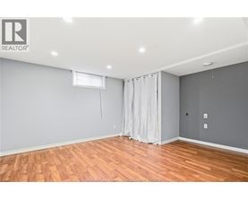A room with wooden flooring and a window with curtains.