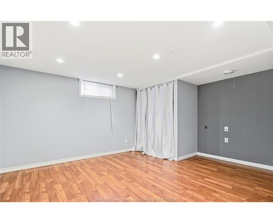 A room with wooden flooring and a window with curtains.