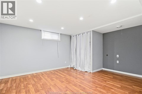A room with wooden flooring and a window with curtains.