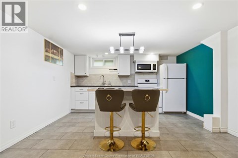 A kitchen with white cabinets and a white refrigerator.
