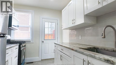A kitchen with white cabinets and a marble countertop.