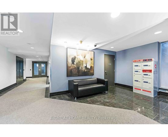 A brokerage office with a black couch and a painting on the wall.