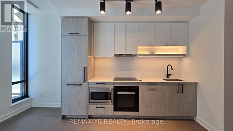A kitchen with a sink, oven, and cabinets.