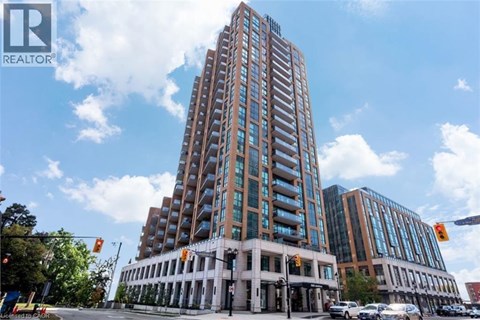 A tall building with a glass facade stands in front of a smaller building with a white facade.
