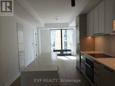 A kitchen with white cabinets and a window with a view of a building outside.