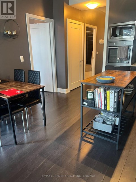 A kitchen with a table and chairs in the foreground and a microwave above the table.