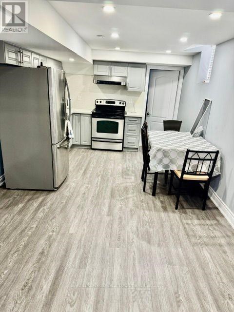 A kitchen with a refrigerator, oven, and a dining table with chairs.