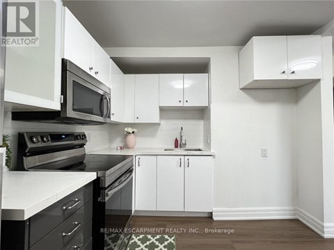 A kitchen with white cabinets and black appliances.