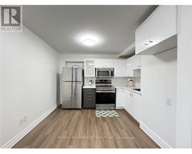 A kitchen with white cabinets and a wooden floor.