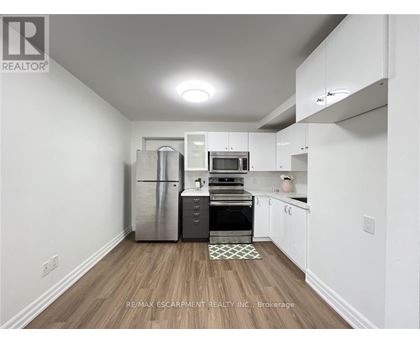 A kitchen with white cabinets and a wooden floor.