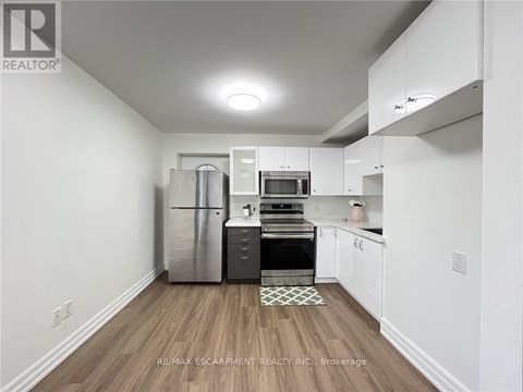 A kitchen with white cabinets and a wooden floor.