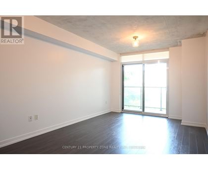 A spacious room with a sliding glass door leading to a balcony.