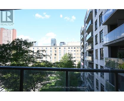 A balcony overlooks a cityscape with buildings and trees.