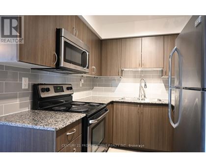 A kitchen with wooden cabinets and a stainless steel refrigerator.