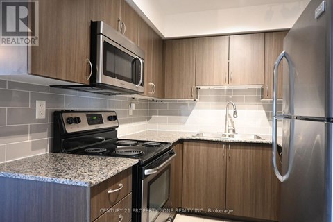 A kitchen with wooden cabinets and a stainless steel refrigerator.