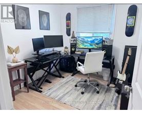 A room with a desk, chair, and two monitors.