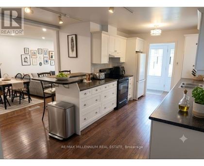 A modern kitchen with white cabinets and a wooden floor.