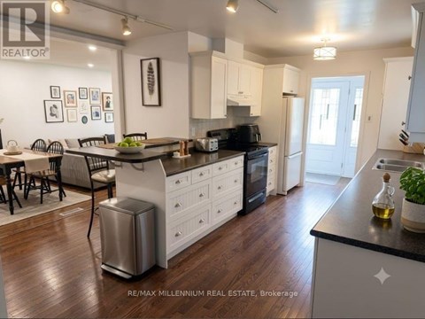 A modern kitchen with white cabinets and a wooden floor.