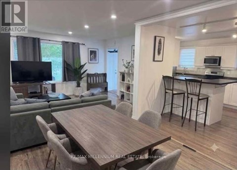A modern living room with a wooden dining table and grey chairs.
