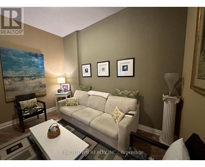 A living room with a white couch and a painting on the wall.
