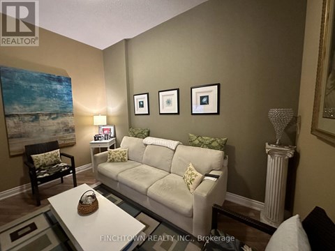 A living room with a white couch and a painting on the wall.