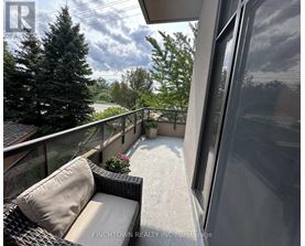 A balcony with a couch and a view of trees and a building.