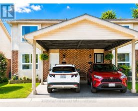 Two cars are parked in front of a house with a covered driveway.