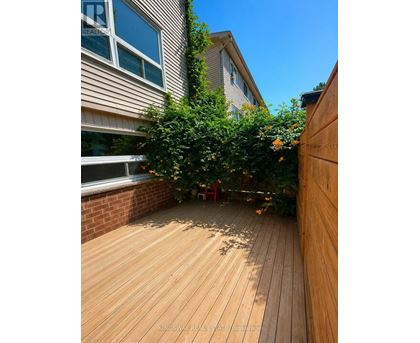 A wooden deck with a red chair and a tree in the middle.