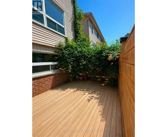 A wooden deck with a red chair and a tree in the middle.