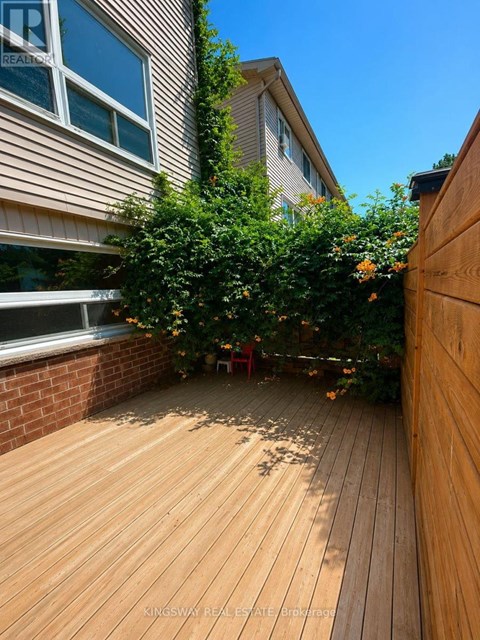 A wooden deck with a red chair and a tree in the middle.