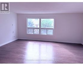 A room with a large window and wooden flooring.