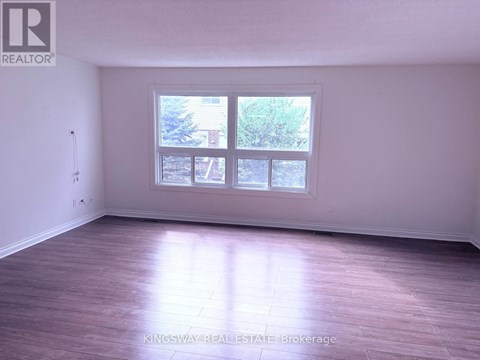 A room with a large window and wooden flooring.