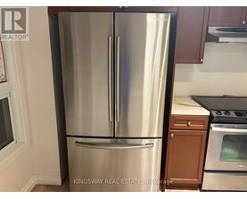 A stainless steel refrigerator in a kitchen with wooden cabinets.