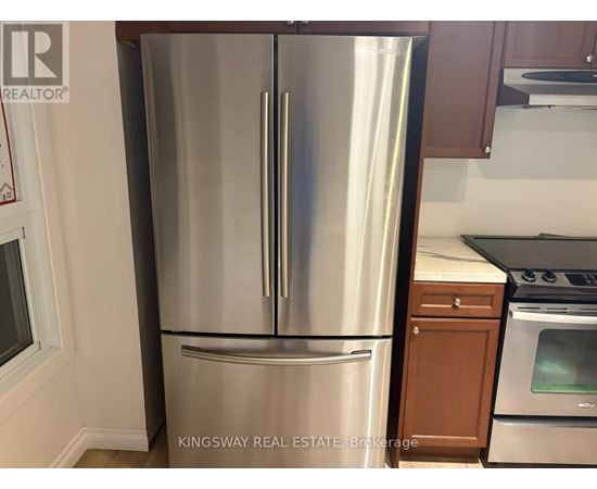 A stainless steel refrigerator in a kitchen with wooden cabinets.
