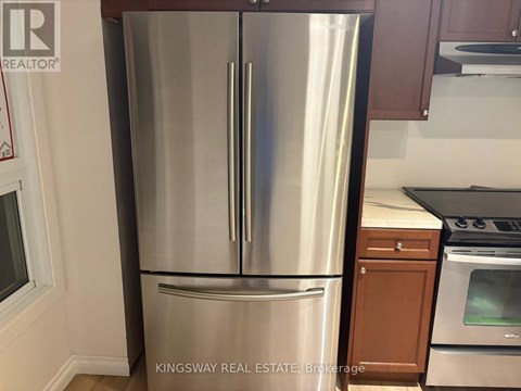 A stainless steel refrigerator in a kitchen with wooden cabinets.