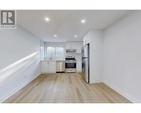 A kitchen with white walls and wooden flooring.