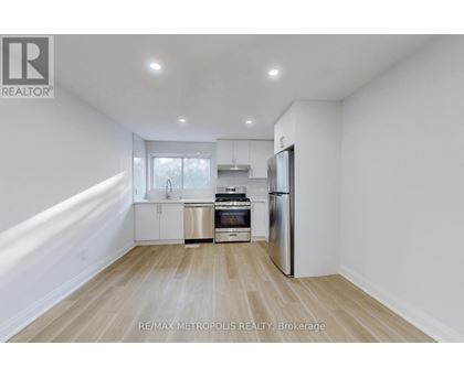 A kitchen with white walls and wooden flooring.