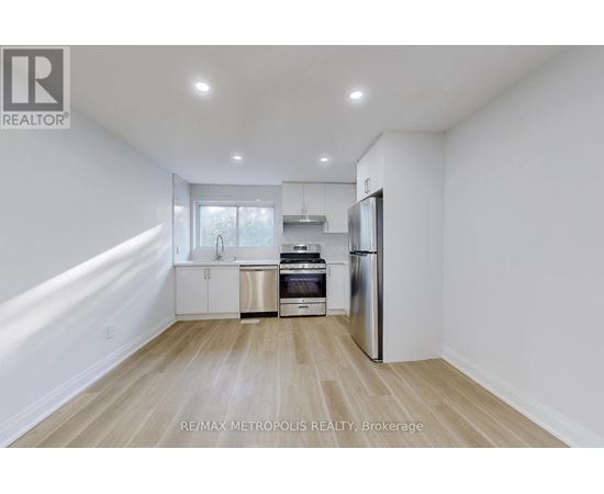 A kitchen with white walls and wooden flooring.