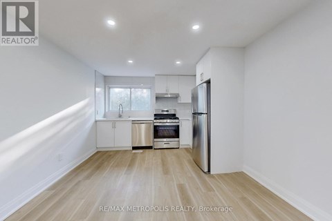 A kitchen with white walls and wooden flooring.