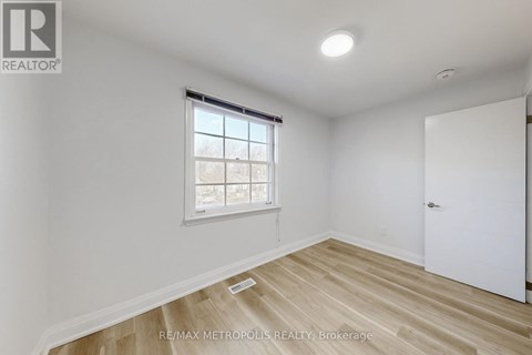 A room with a window and wooden flooring.