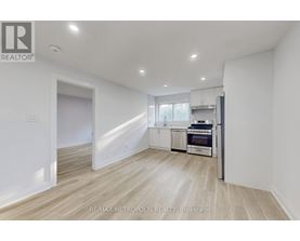 A spacious, empty room with a kitchenette in the background.