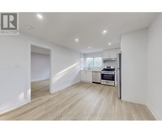 A spacious, empty room with a kitchenette in the background.