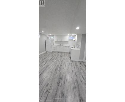 A spacious kitchen with white cabinets and a refrigerator.