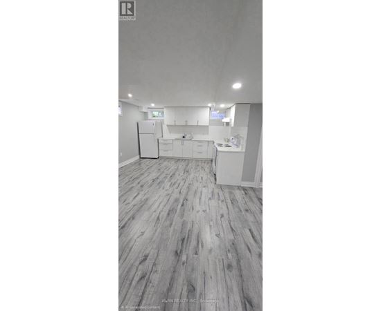 A spacious kitchen with white cabinets and a refrigerator.