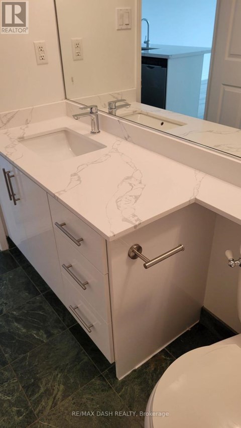A bathroom with a sink, mirror, and toilet.