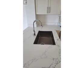 A sink in a marble countertop with a chrome faucet.