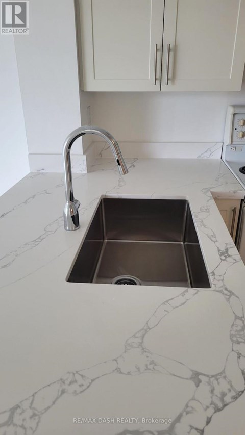 A sink in a marble countertop with a chrome faucet.