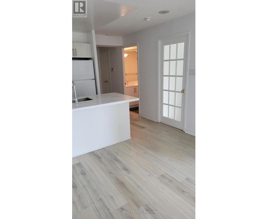 A white kitchen with a refrigerator and sink.