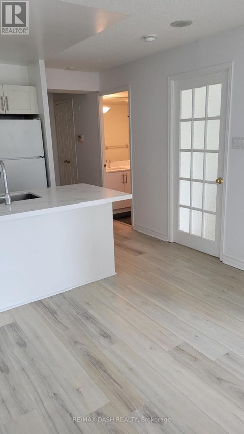 A white kitchen with a refrigerator and sink.